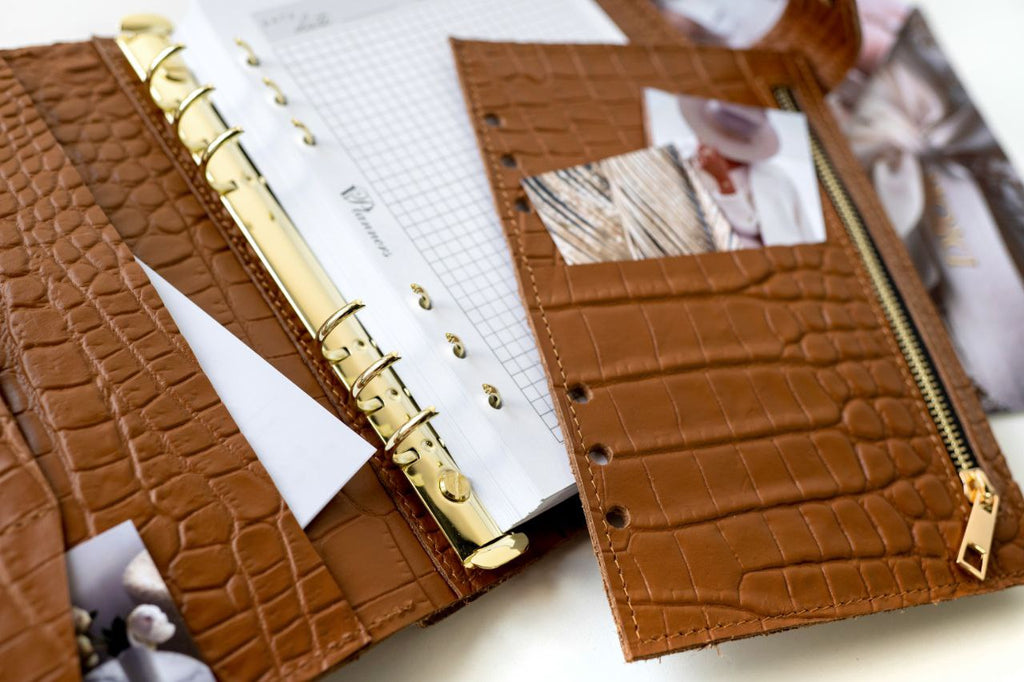 Close-up of a rare brown leather A5 notebook cover with gold rings and zip pocket, showcasing its elegant texture and details.