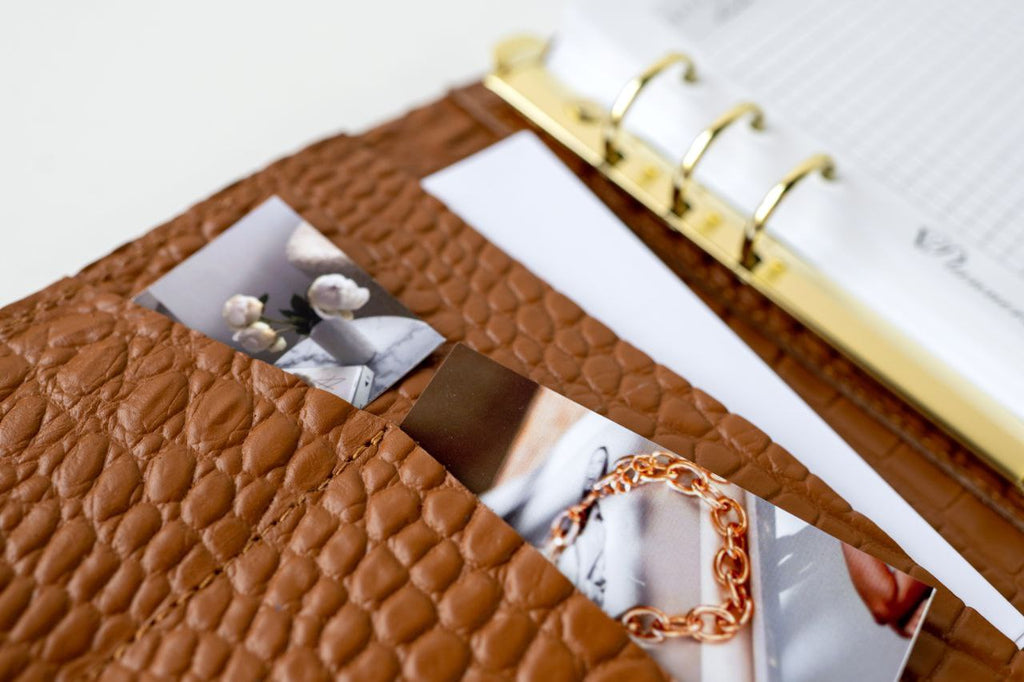 Close-up of a rare brown leather notebook cover with cards and document slots, showcasing its texture and interior design.
