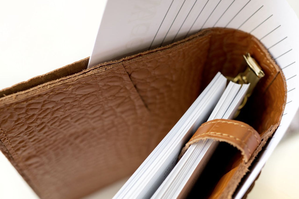 Close-up of a rare brown leather A5 notebook cover with documents and binder rings visible.