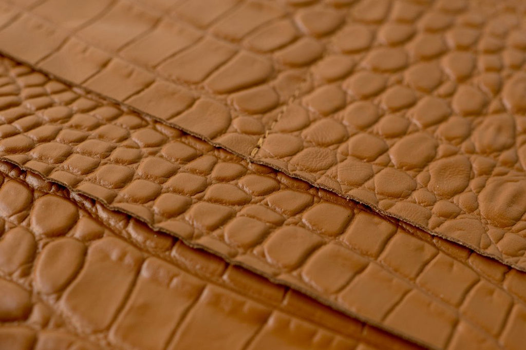 Close-up of rare brown leather with a textured, croc-like pattern, ideal for notebook covers and accessories.