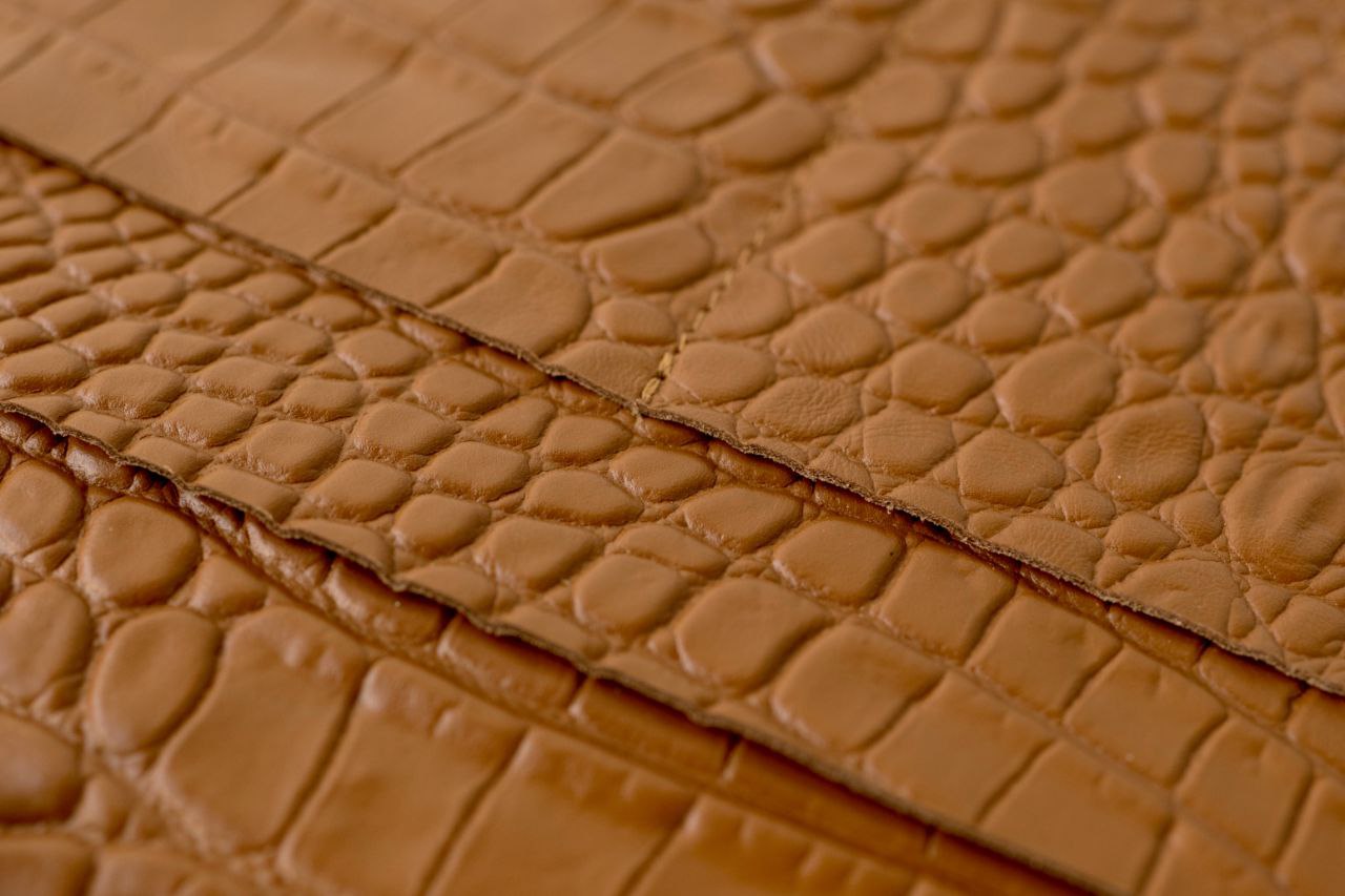 Close-up of rare brown leather with a textured, croc-like pattern, ideal for notebook covers and accessories.