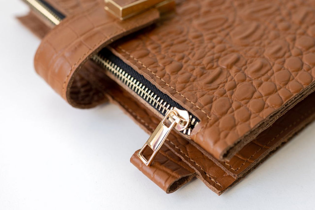 Close-up of a rare brown leather notebook cover with a gold zipper detail.