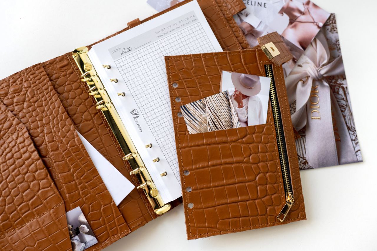 Rare brown leather A5 notebook cover with zipper pocket and binder rings, showcasing pages and stylish accessories.